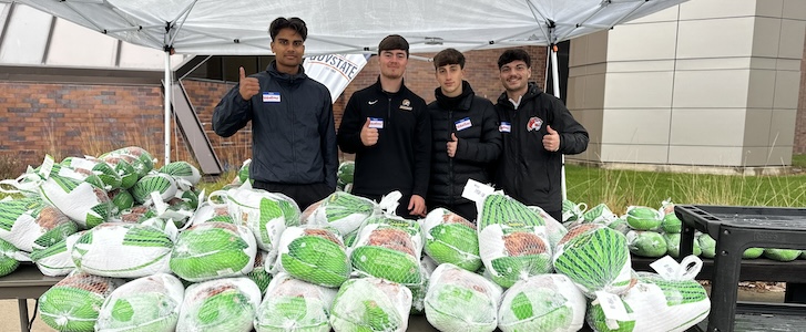 Students giving thumbs up in front of a pile of frozen turkeys